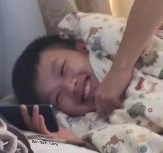 ảnh meme cậu bé nằm xem điện thoại tủm tỉm cười
